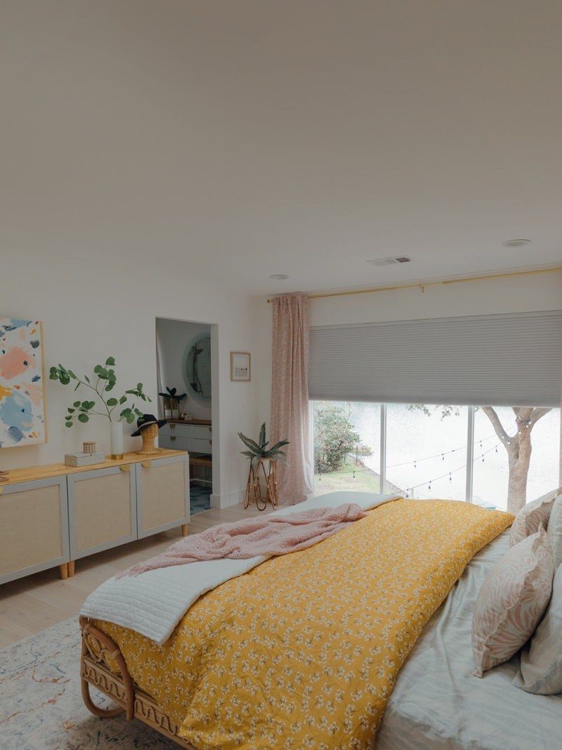 Bedroom with yellow bedding, light-colored furniture, and a window with a view.