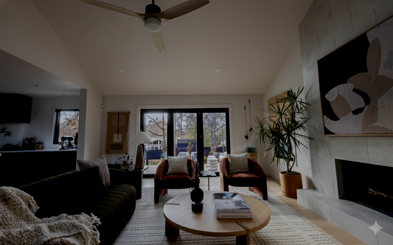 Living room with black sofa, two red chairs, wooden coffee table, and large fireplace.