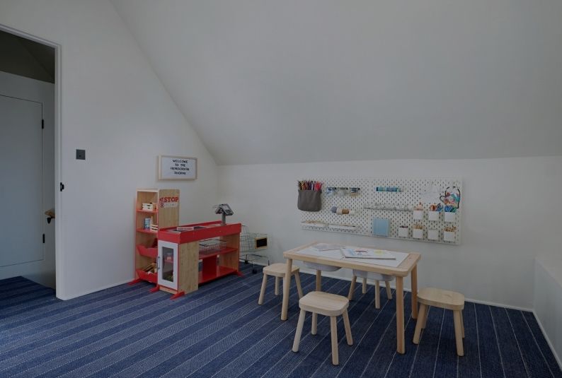 Playroom with blue striped carpet, wooden furniture, and a play kitchen.