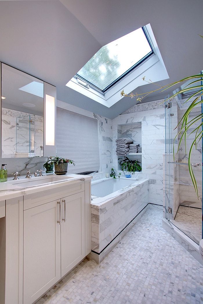 Bright white bathroom with marble tile, a bathtub, and a skylight.
