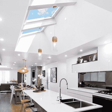 Modern white kitchen with skylights, island, and pendant lights.