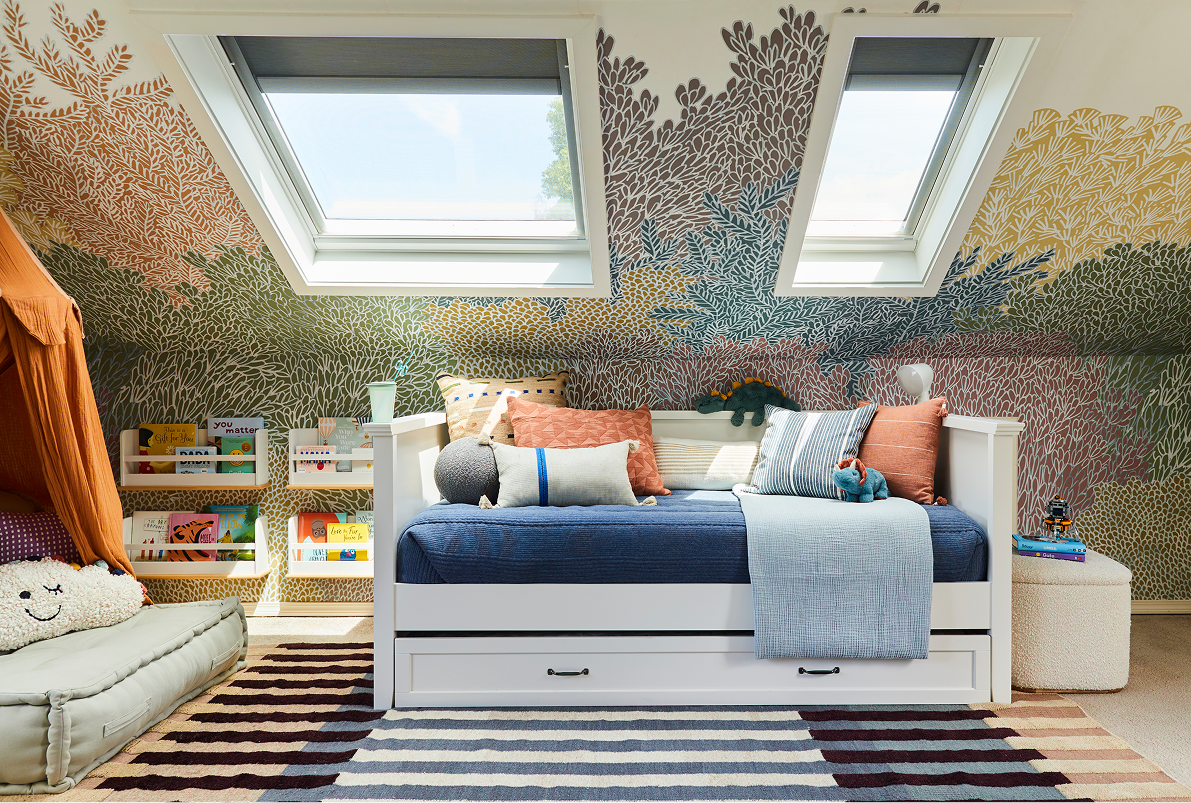 Bedroom with daybed, skylights, colorful mural, bookshelves, and rug.