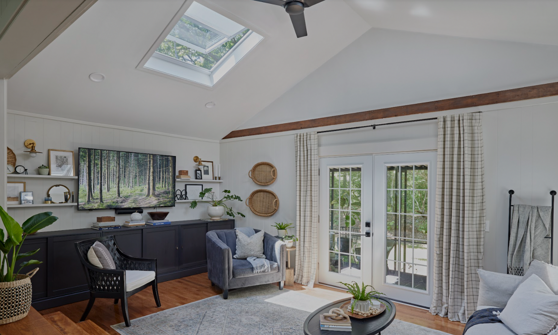 Living room with skylight, TV, blue armchair, and French doors leading to a balcony.