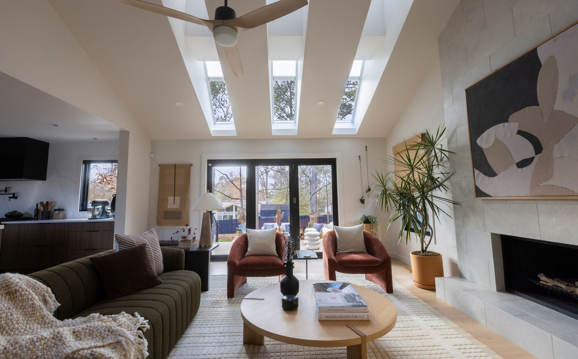Living room with skylights, sofa, fireplace, armchairs, and round coffee table.