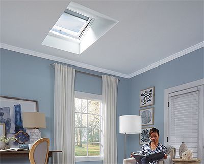 Living room with blue walls, skylight, and woman reading.