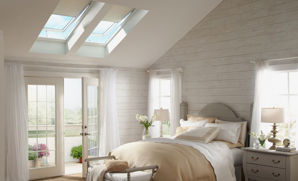 Bedroom with skylights, white walls, and a bed. Natural light fills the room.