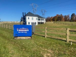 A blue sign in a grassy field with a house in the background.