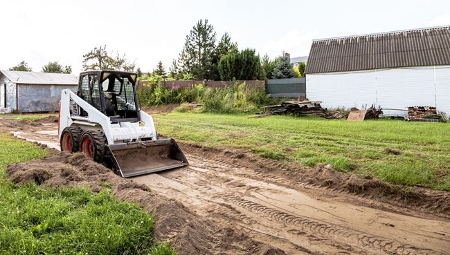 A bulldozer is driving down a dirt road in a field.