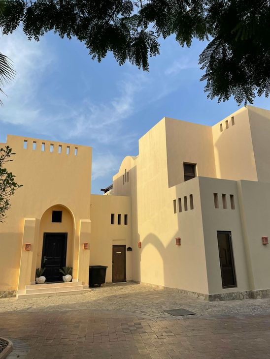 A woman is sitting at a desk with a laptop and a vase of flowers.