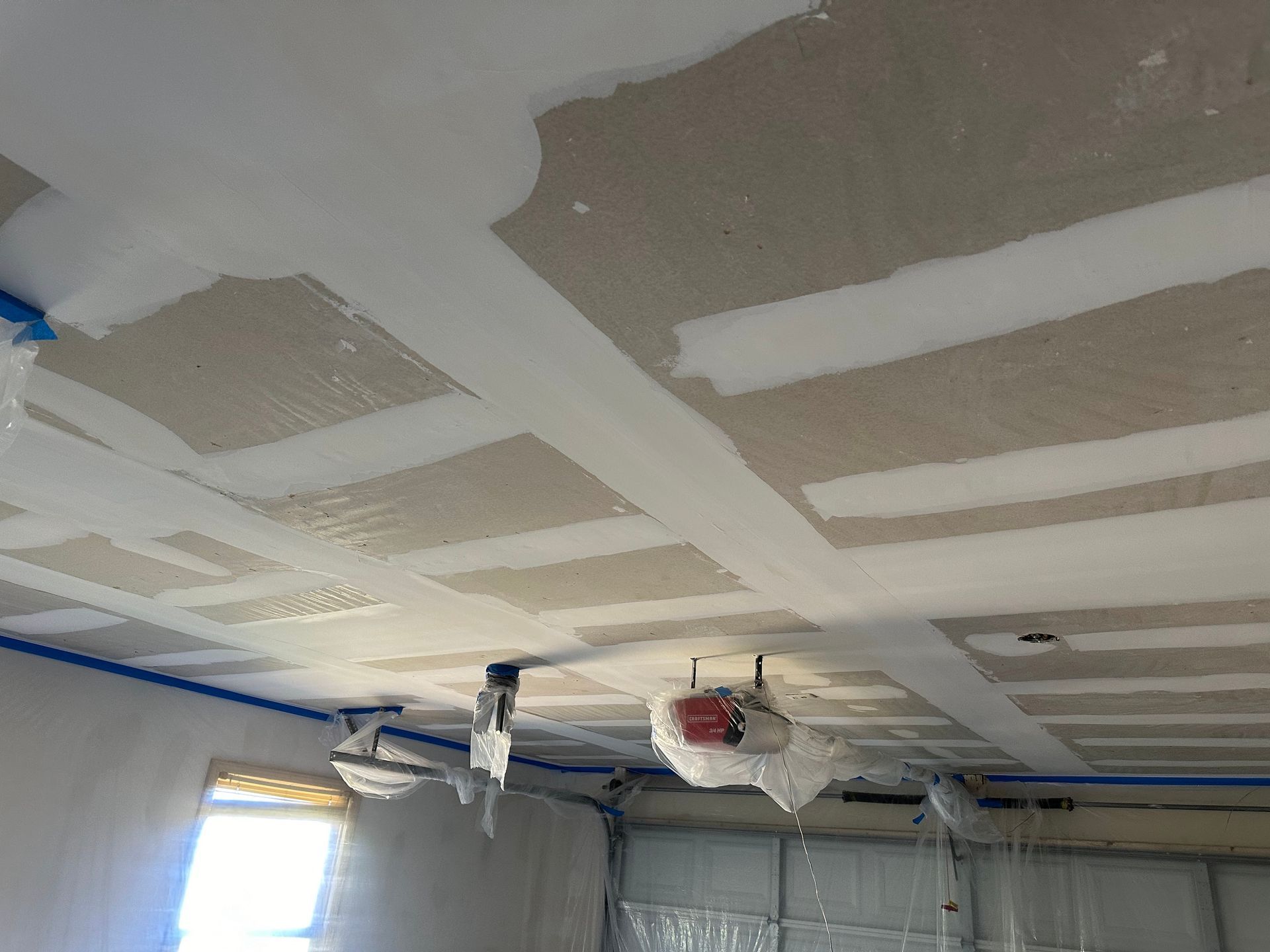 Partially finished ceiling with drywall patches, exposed wiring, and hanging light fixtures in a room