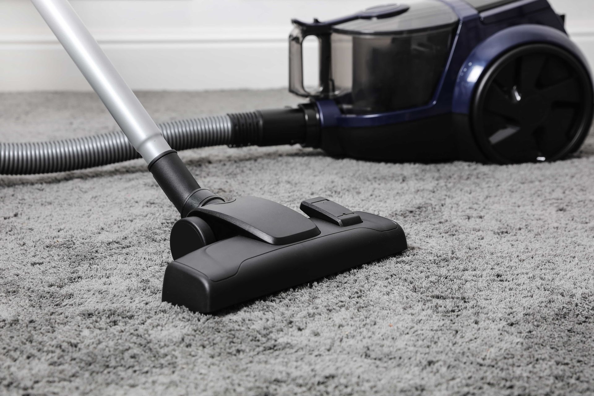 Vacuum cleaner on a gray carpet, with the vacuum head positioned over the carpet.