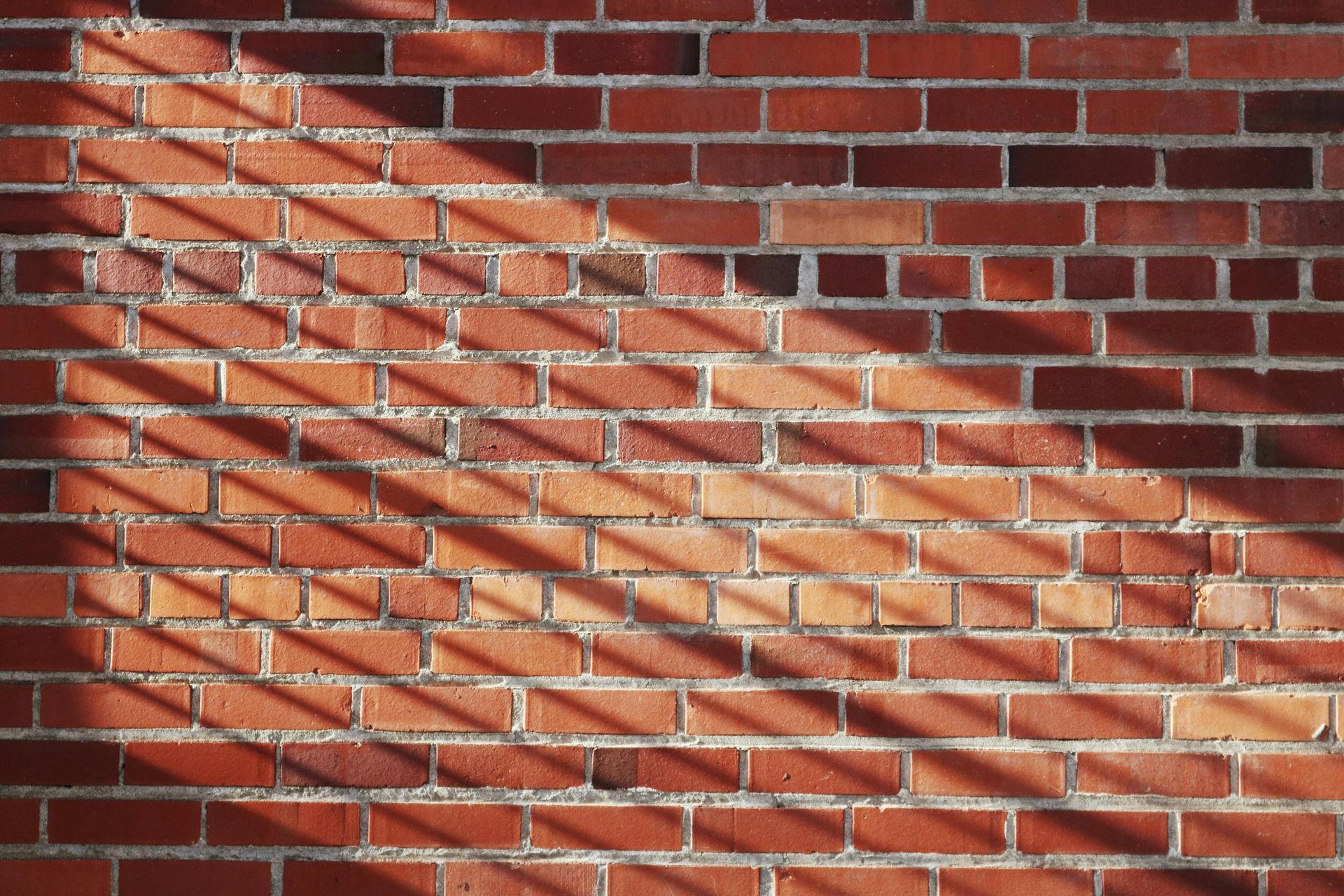 Red brick wall with shadows from an unseen source.