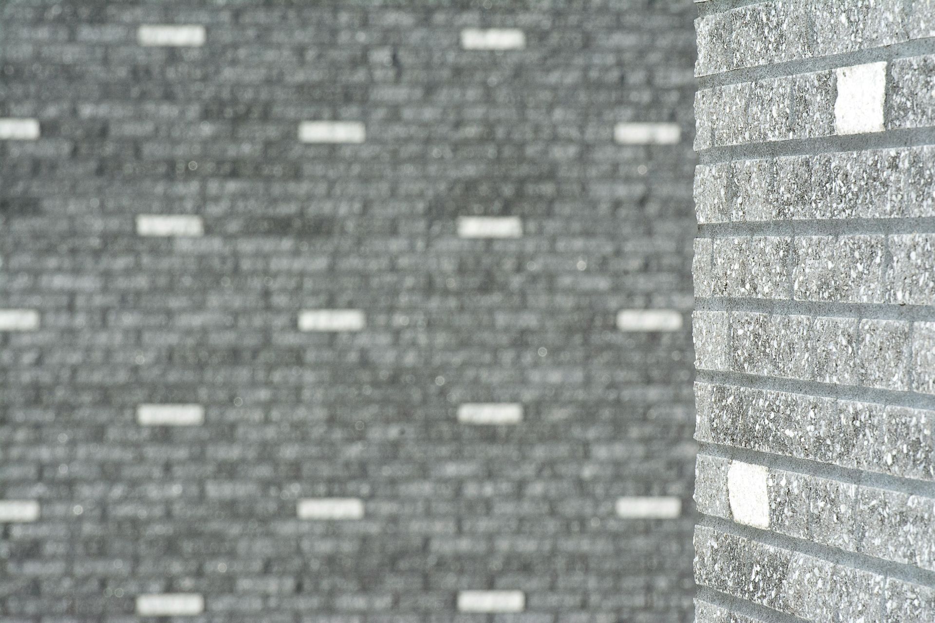 Gray brick wall with scattered white accents and a corner in sharp focus.