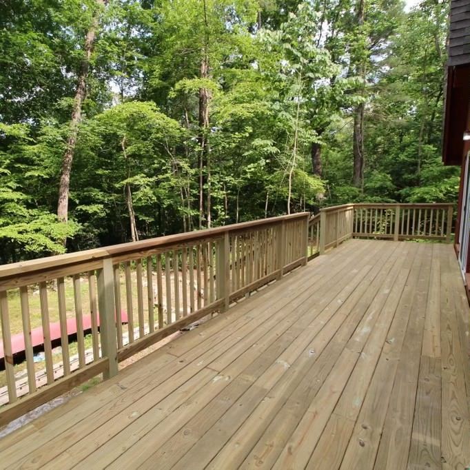 A large wooden deck with trees in the background