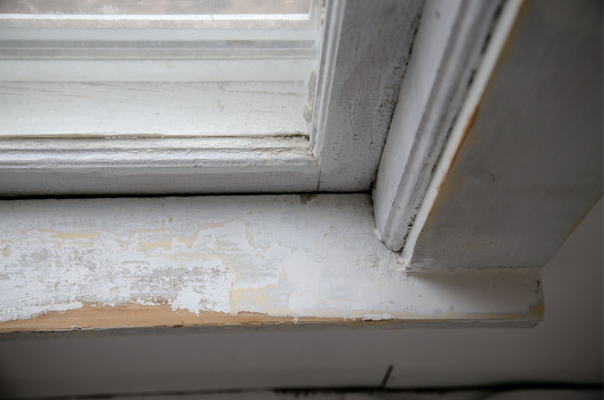 A close up of a window sill with peeling paint.