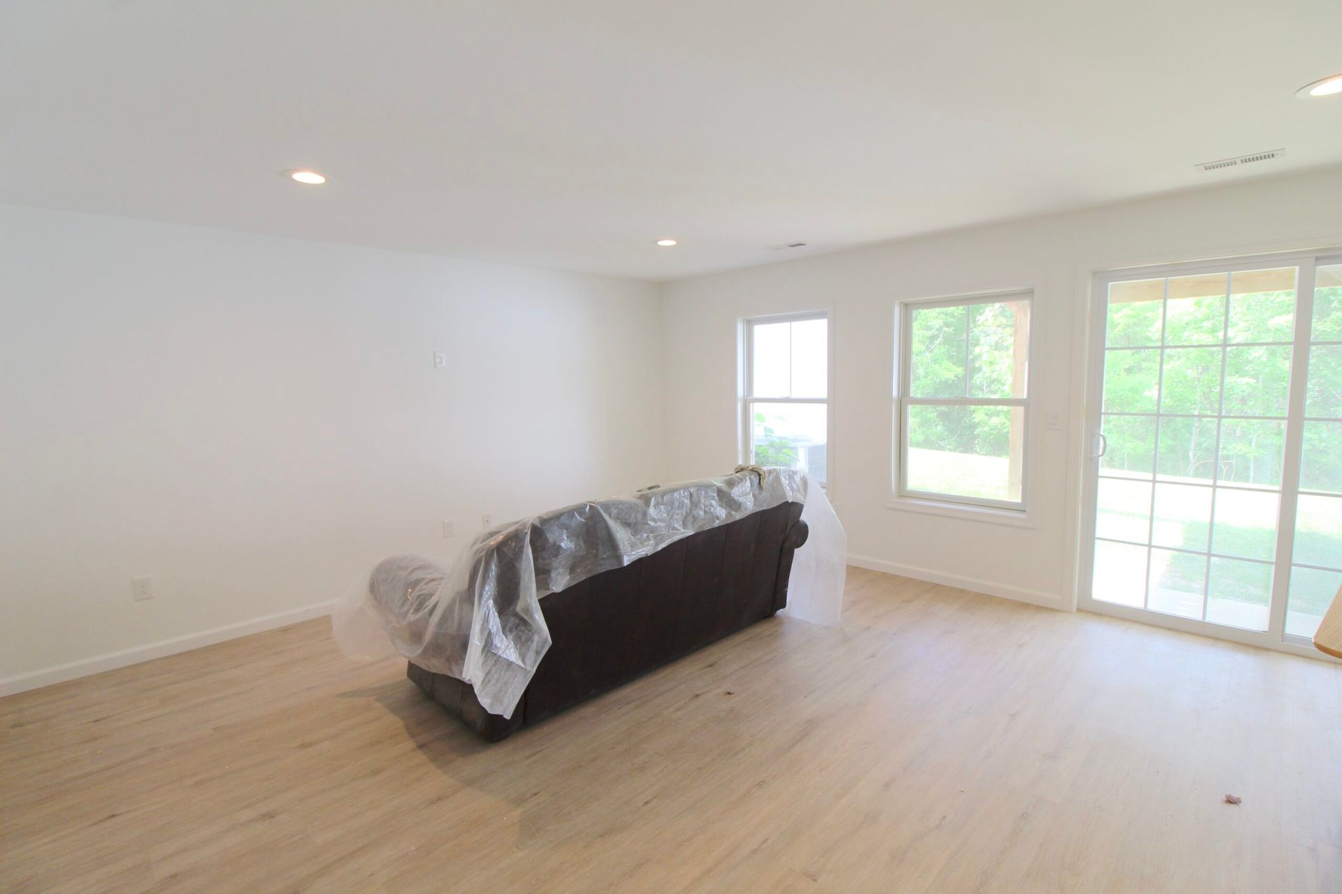 An empty living room with a couch and two windows.