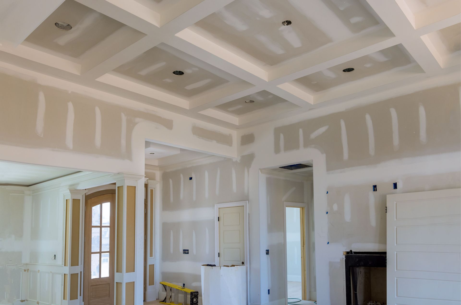 A room in a house under construction with drywall on the walls and ceiling.