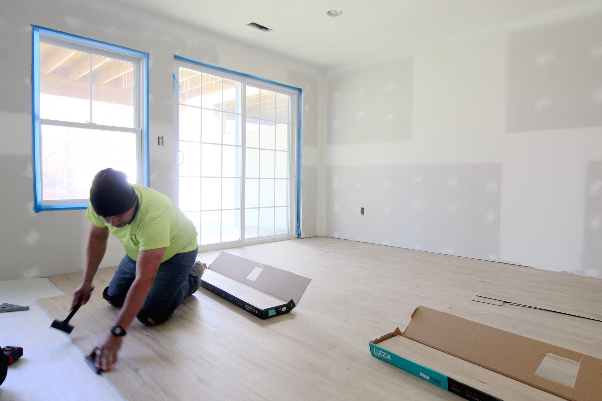 A man is kneeling on the floor in an empty room.