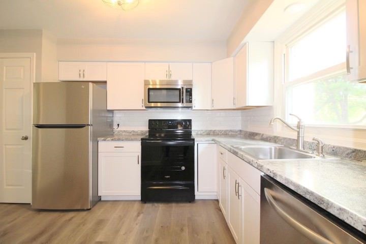 A kitchen with stainless steel appliances and white cabinets.