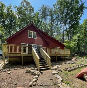 A red house with a wooden deck and stairs