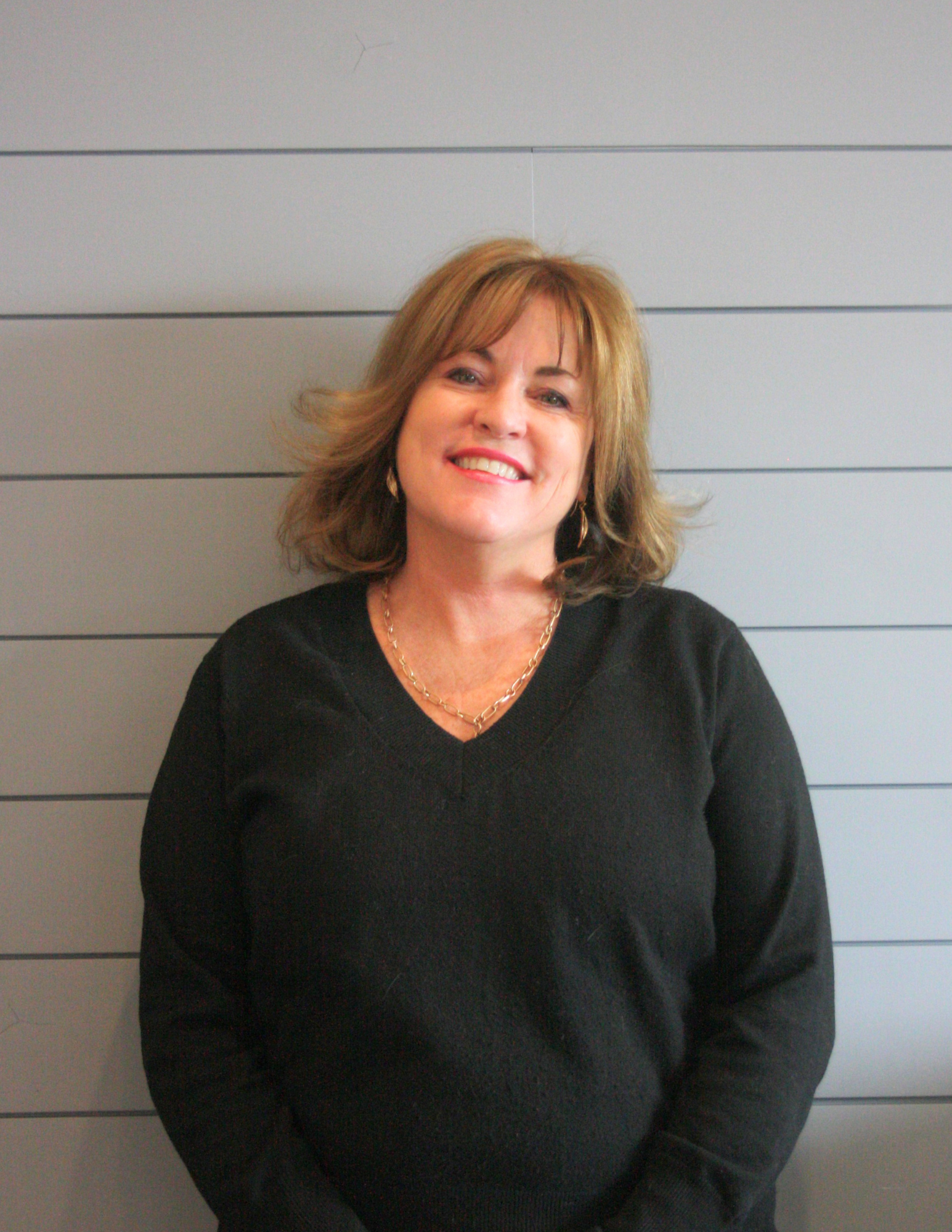 A woman in a black sweater is smiling for the camera