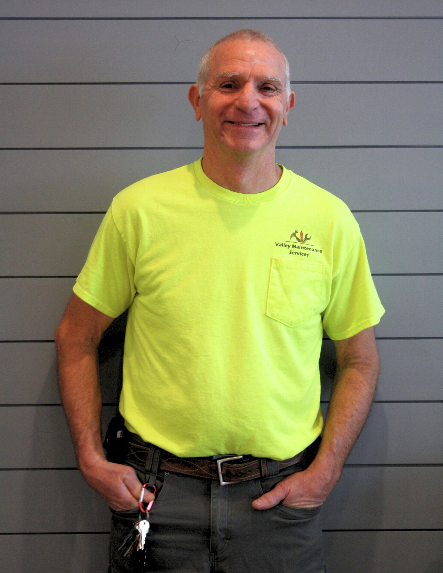 A man wearing a neon yellow t-shirt is standing with his hands in his pockets
