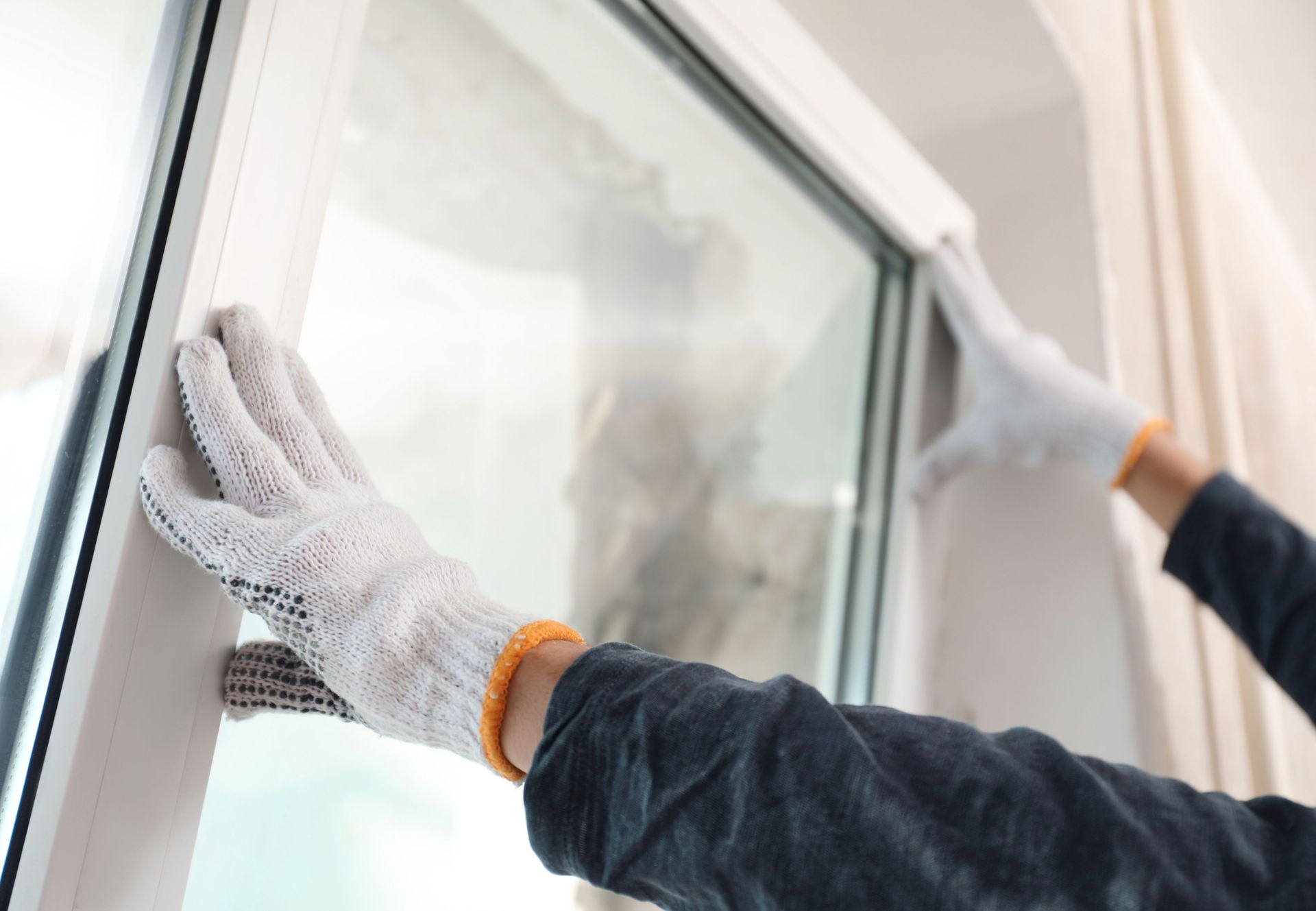 A person wearing gloves is cleaning a window.