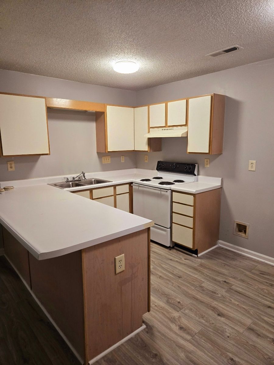 A kitchen with a stove , sink , and cabinets.