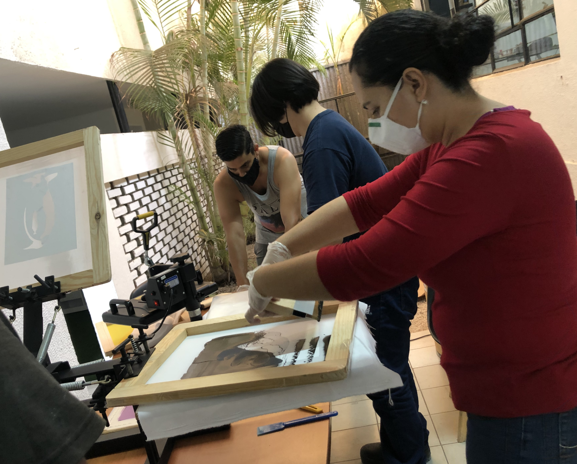 Un grupo de personas está trabajando en una máquina de serigrafía.