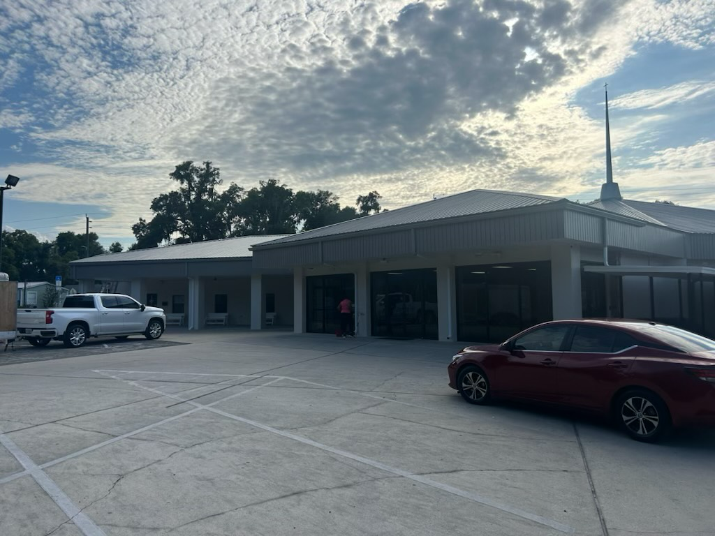 a red car is parked in a parking lot in front of a building