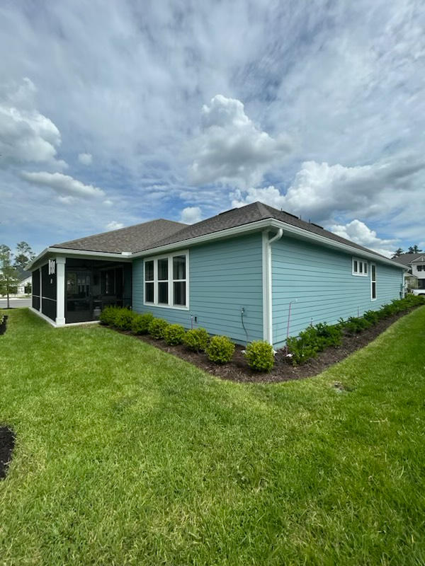 a blue house with a screened in porch is sitting on top of a lush green lawn