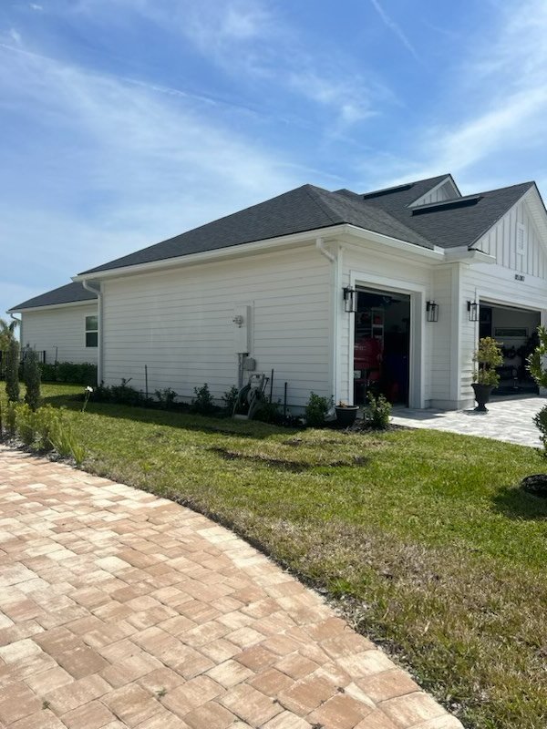 a white house with a garage and a brick driveway in front of it