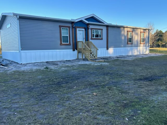 a mobile home with a wooden deck and stairs is sitting in the middle of a grassy field