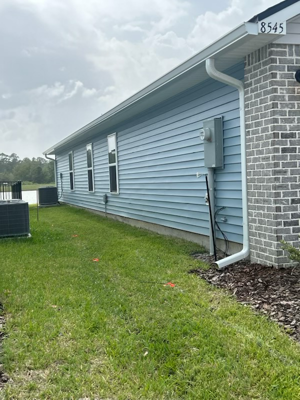 a blue house with a brick wall and a lot of grass in front of it