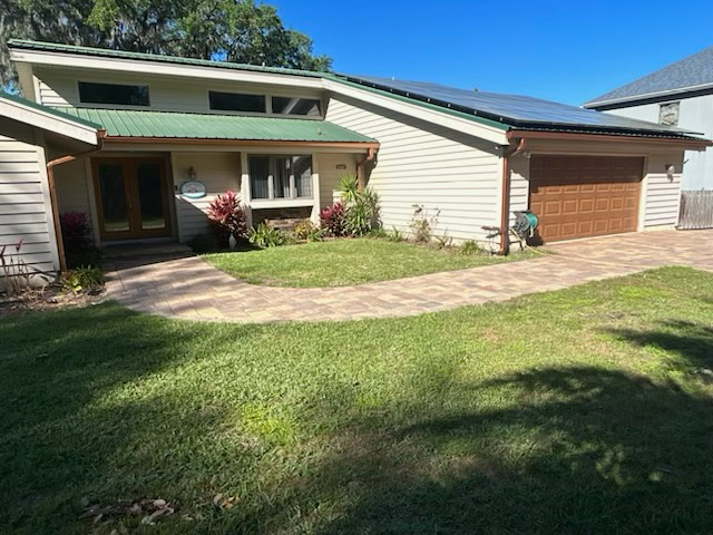 a white house with a green roof and a brown garage door