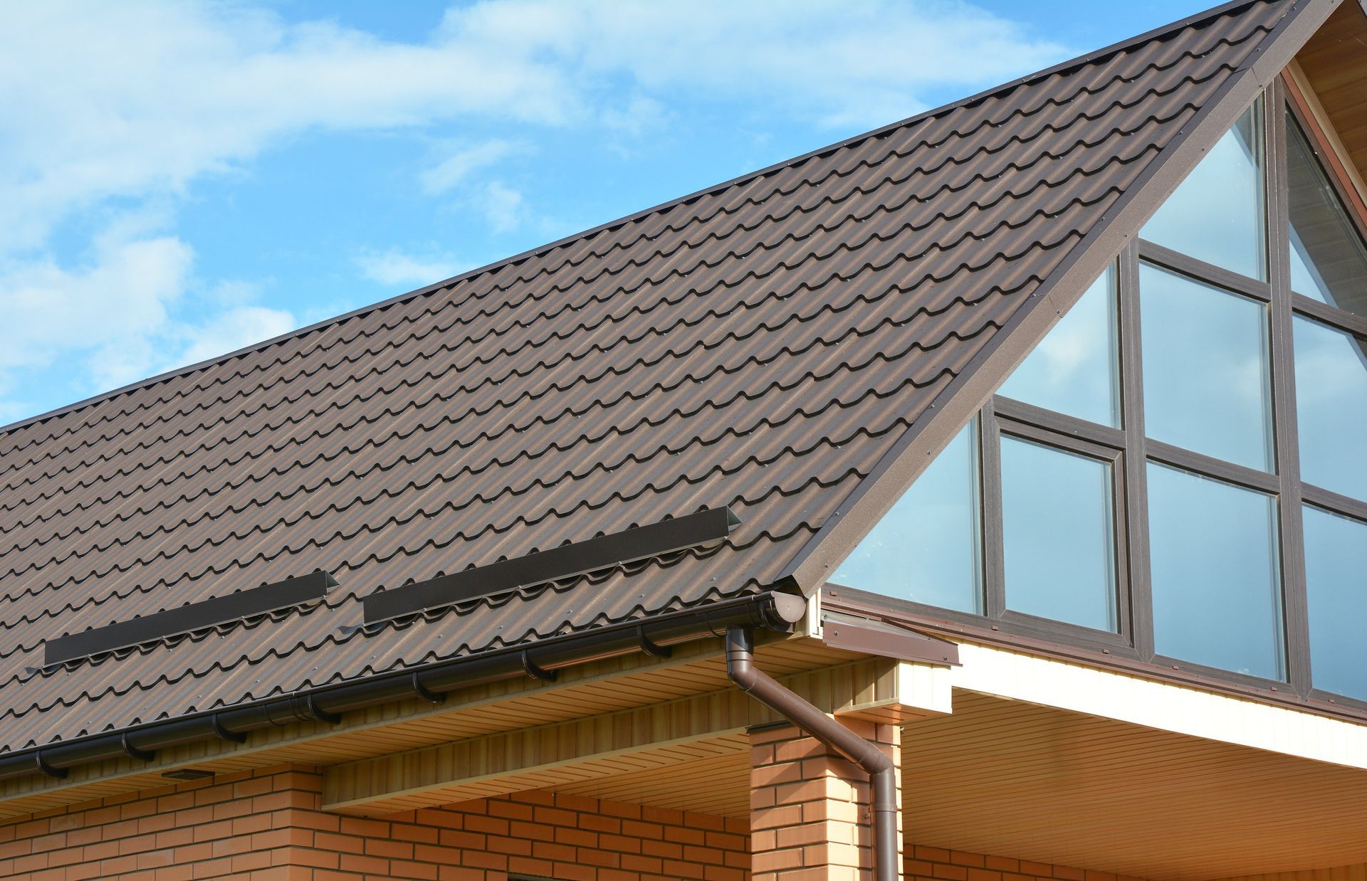 a brick house with a brown roof and large windows