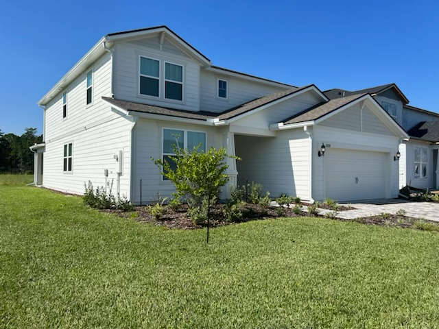 A large white house with a blue truck parked in front of it.
