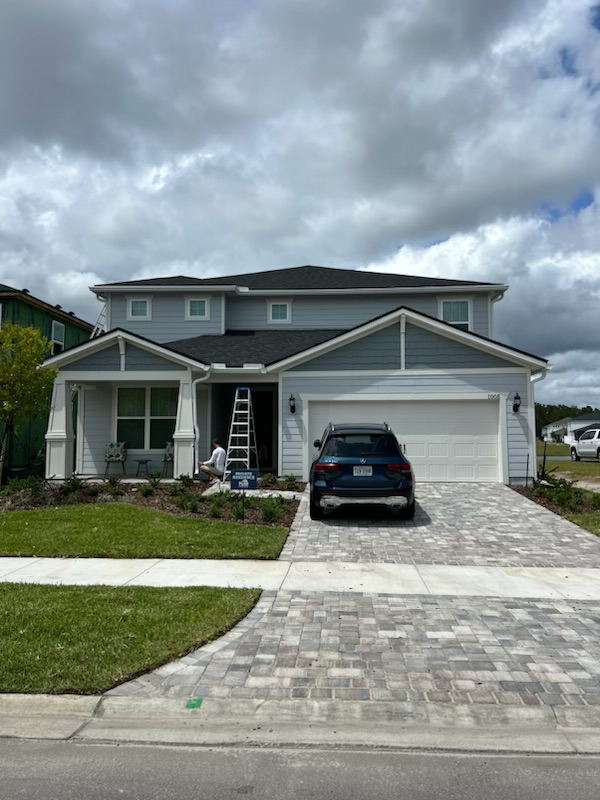 A large white house is sitting on top of a lush green field.