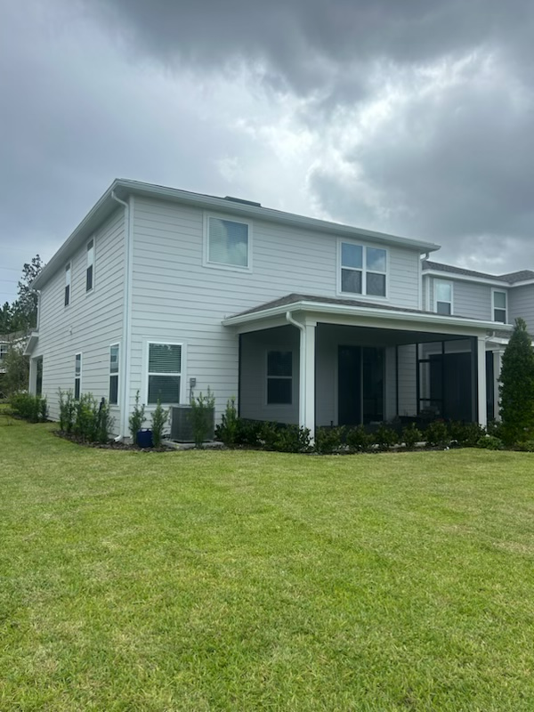 A white house with a black garage door is being built by ryan builders