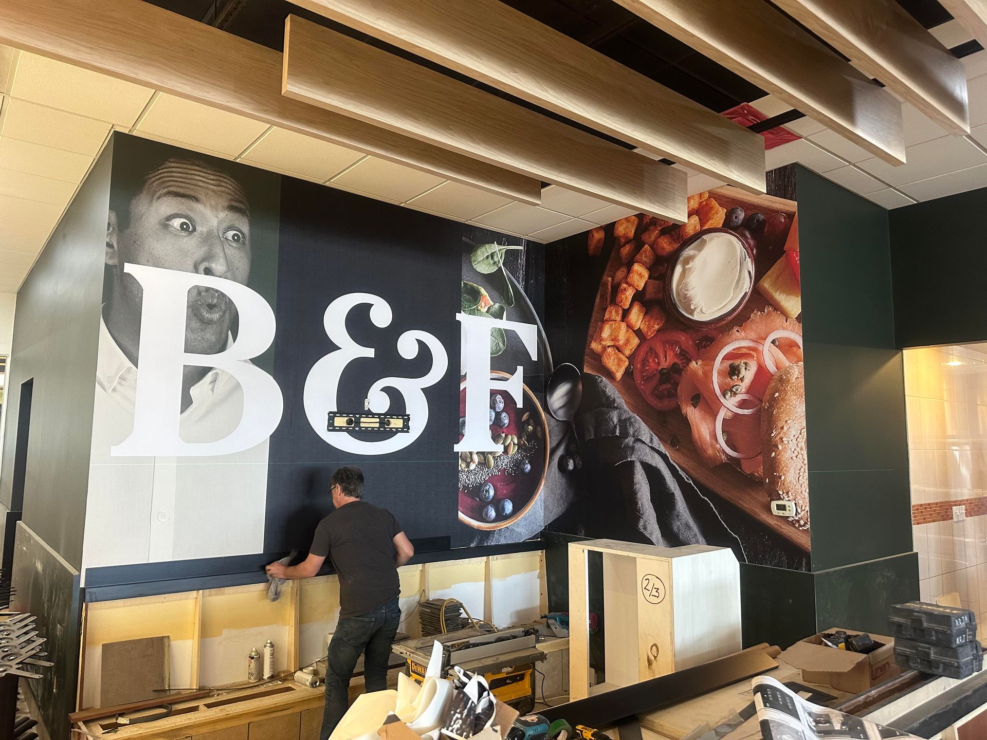 Un homme se tient devant une grande fresque murale qui dit b&f.