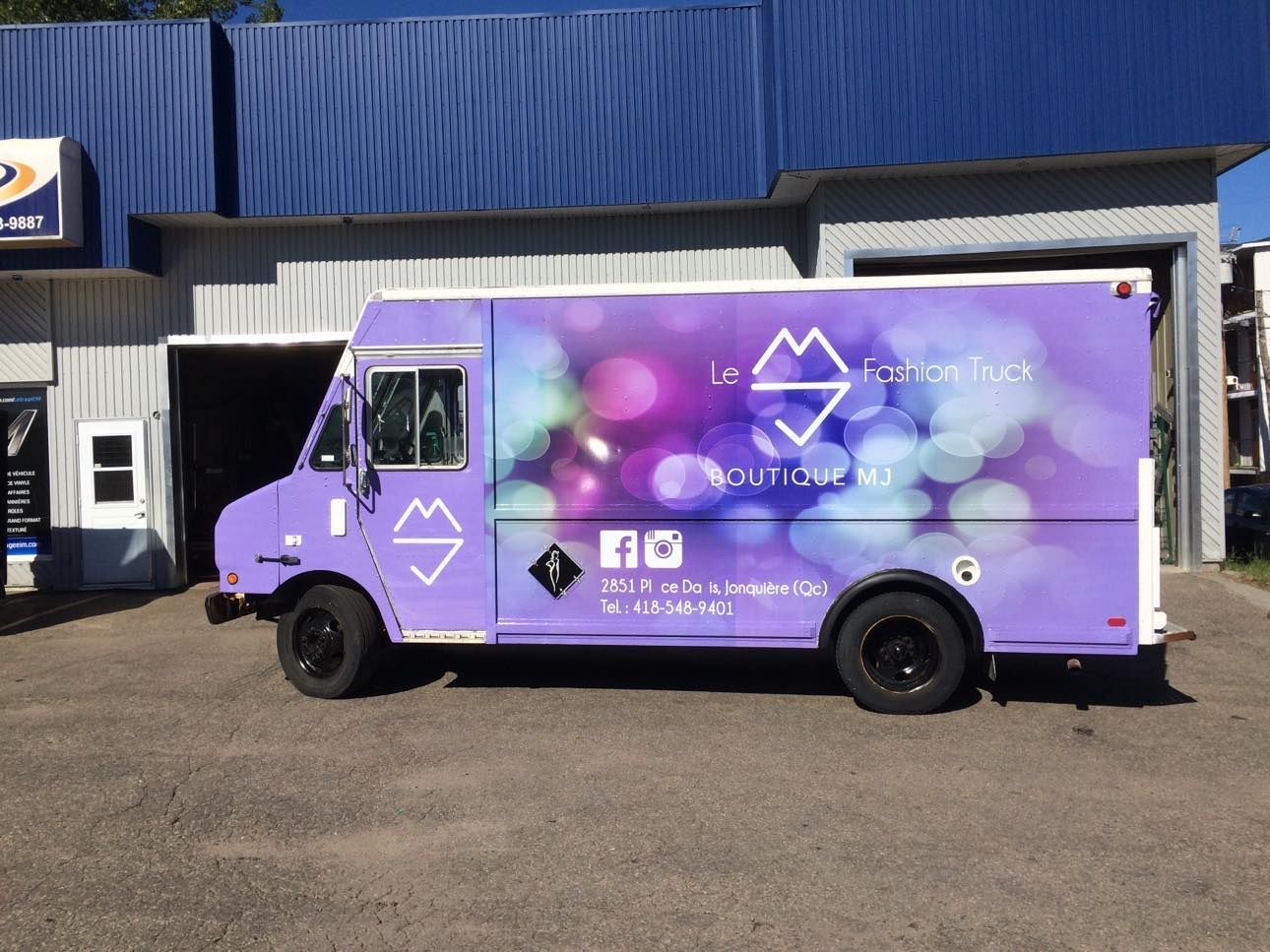 Un food truck violet est garé devant un immeuble