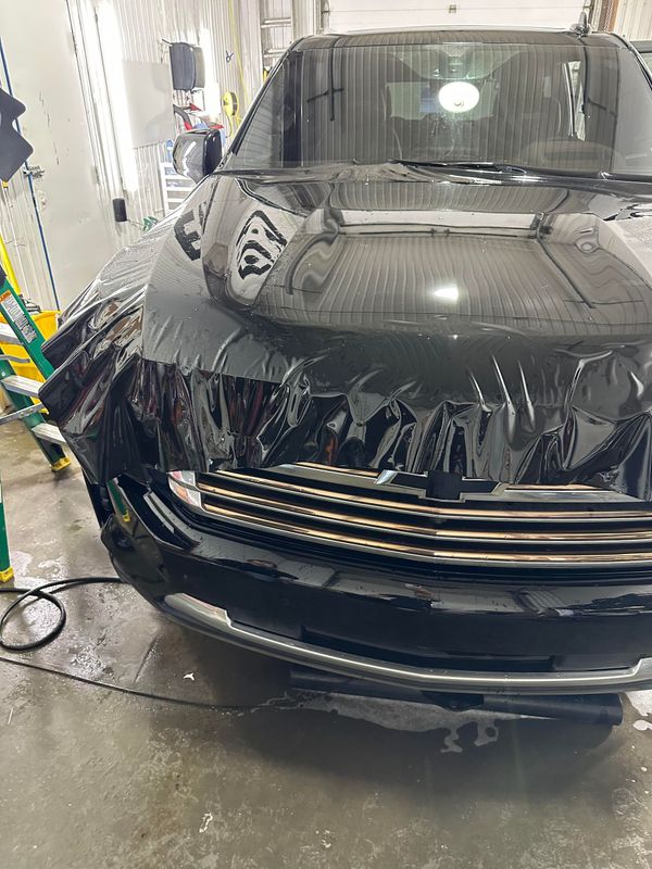 Une voiture noire est enveloppée dans du plastique dans un garage.