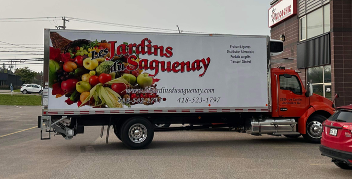 Un camion avec une photo de fruits sur le côté est garé dans un parking.