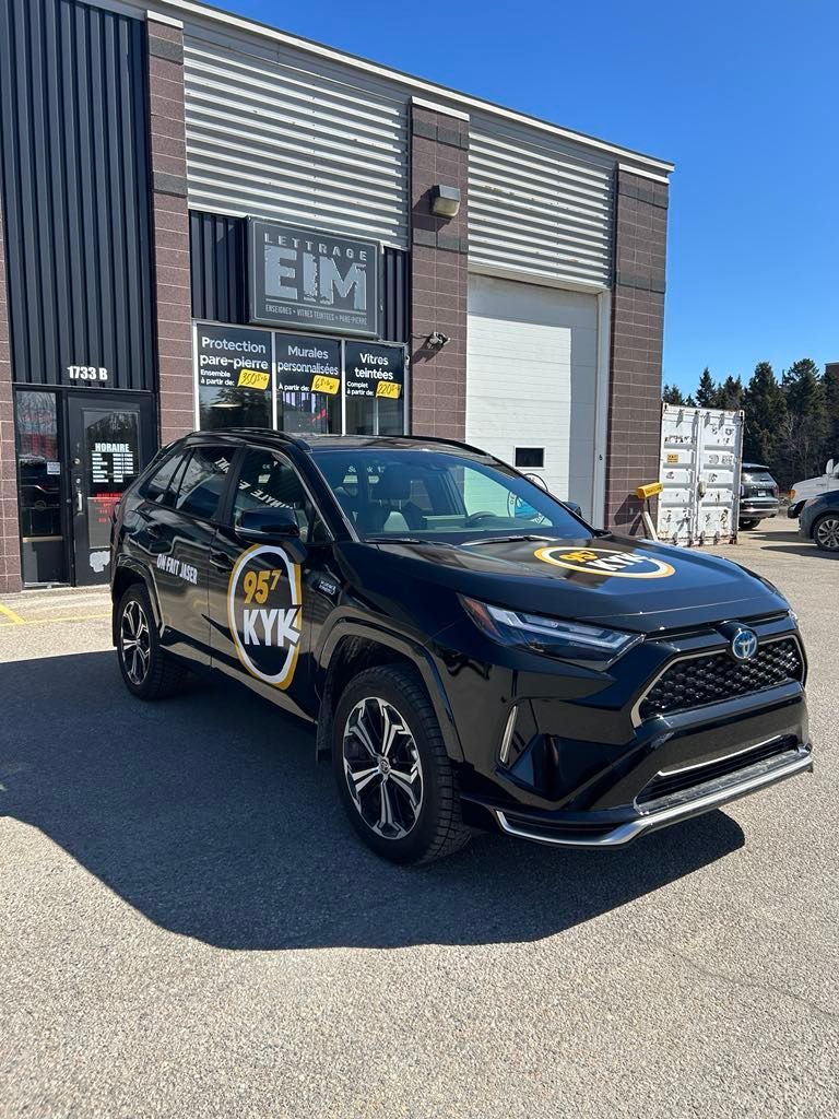 Une personne tient un morceau de plastique au-dessus d’une voiture.