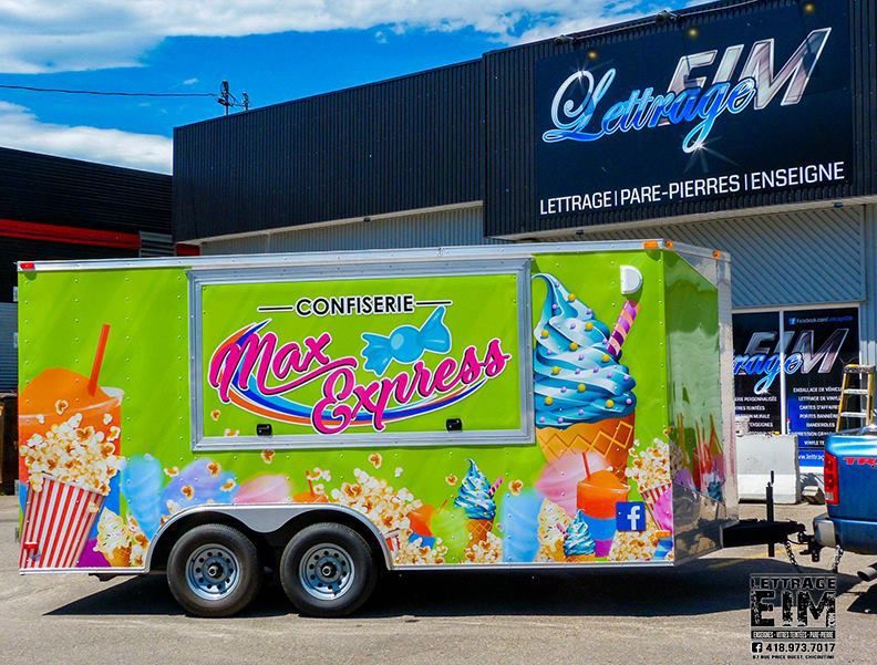 Une caravane verte avec des cornets de glace est garée devant un immeuble.