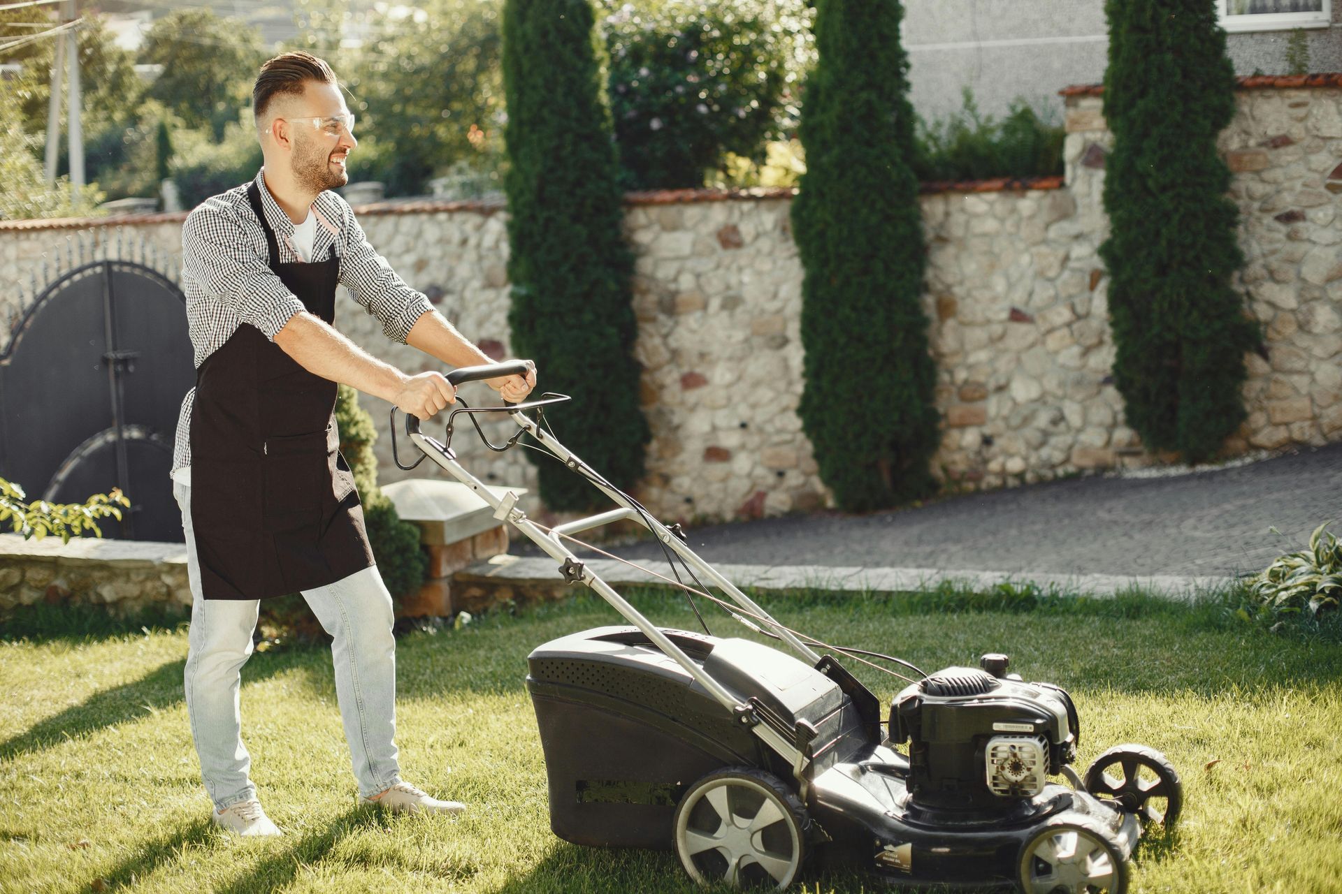 A man is mowing his lawn with a lawn mower.