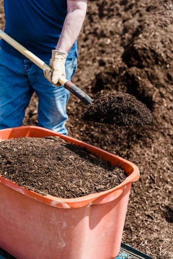 A man is digging in a pile of dirt with a shovel.