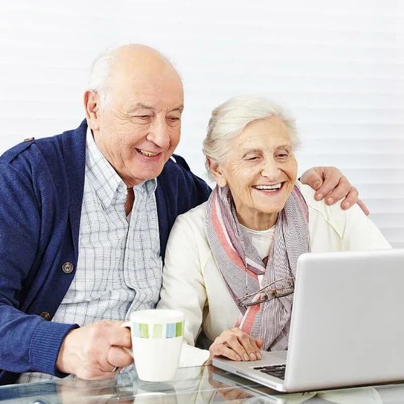 Two Senior Looking at A Laptop — Dementia Care — Assured Senior Living