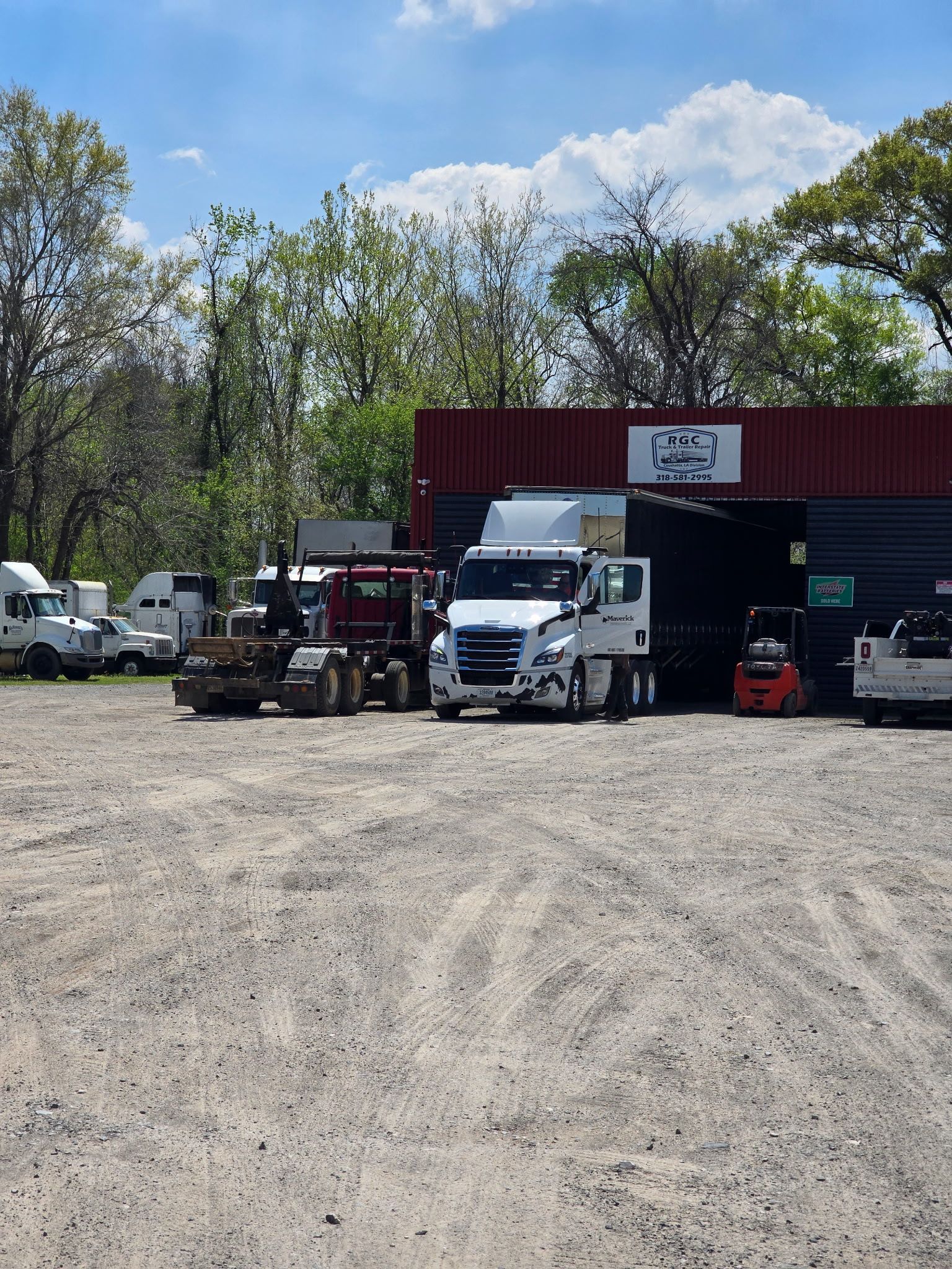 A lot of trucks are parked in front of a building that says ' trucks ' on it