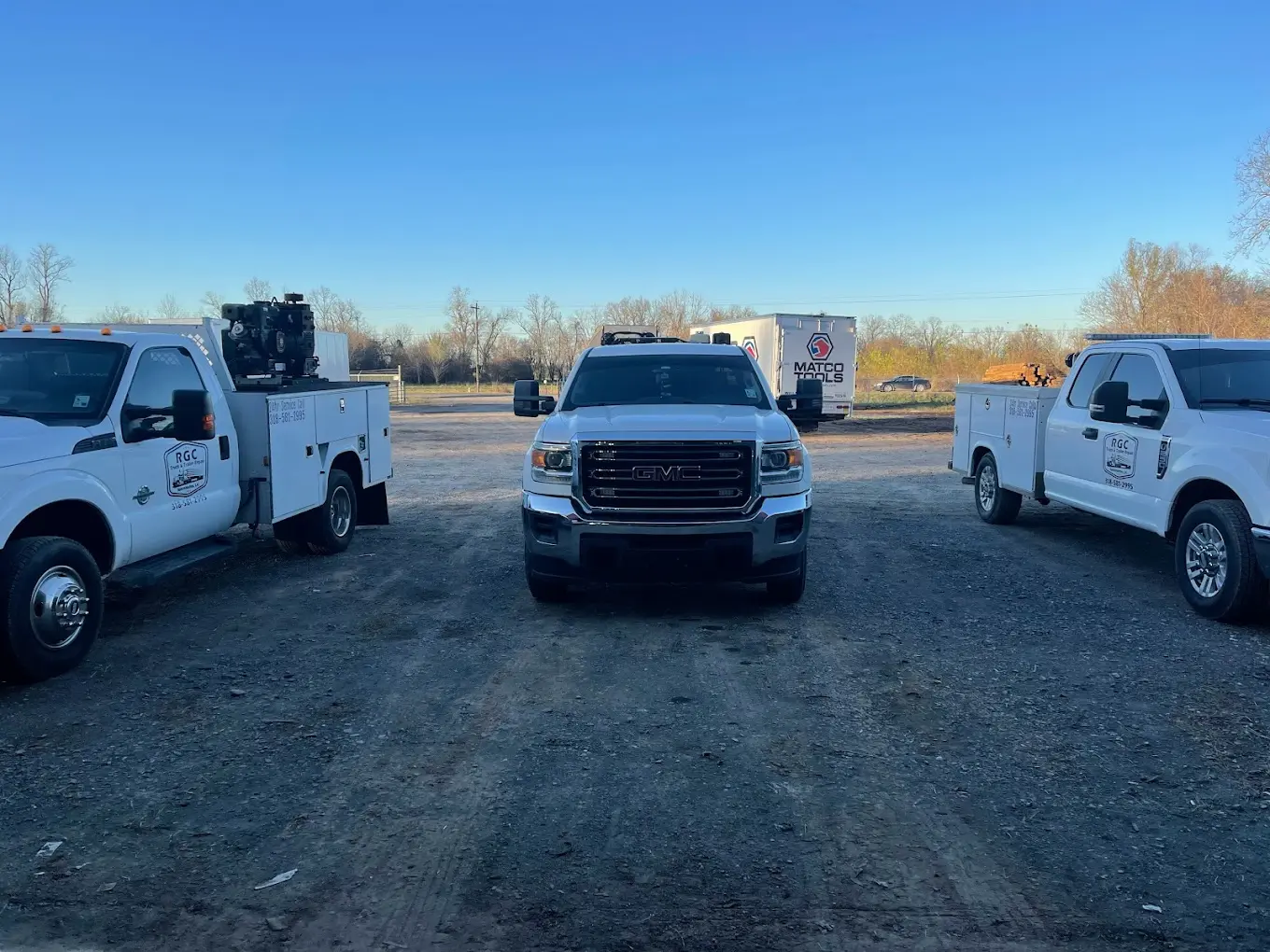 Three gmc trucks are parked in a parking lot